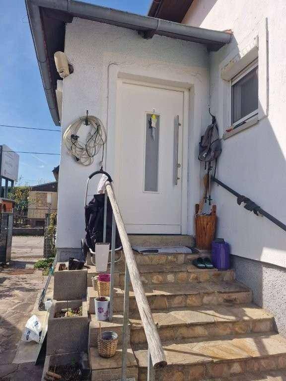 Eingangsbereich des Hauses mit Steintreppe und weißer Haustür.