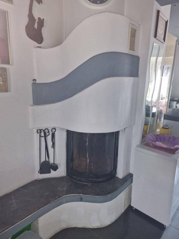 Moderner Kamin mit geschwungenem Design und dunkler Ablagefläche.
