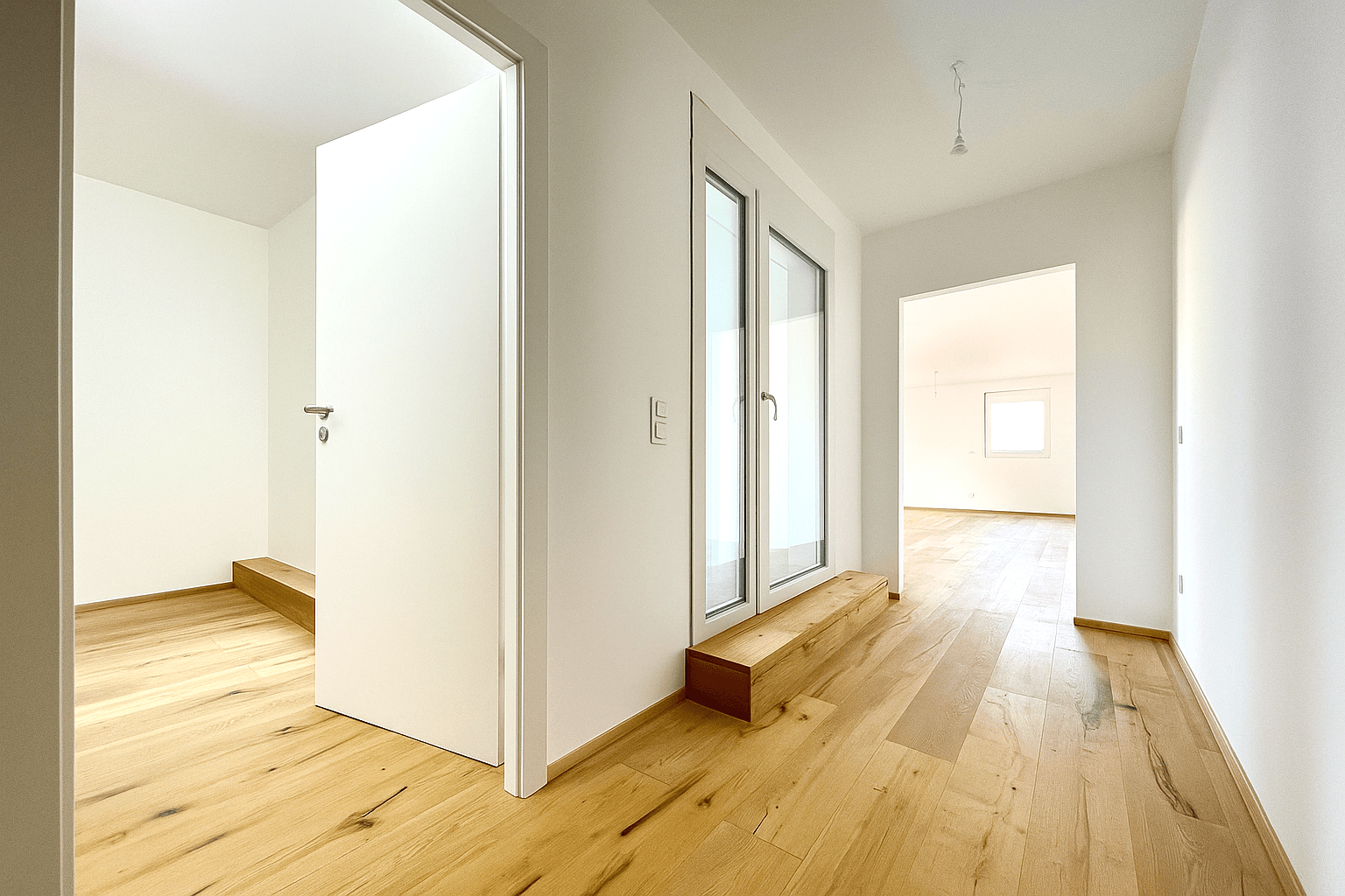 Helles Schlafzimmer mit Holzboden und großen Fenstern, die den Raum mit Licht füllen.