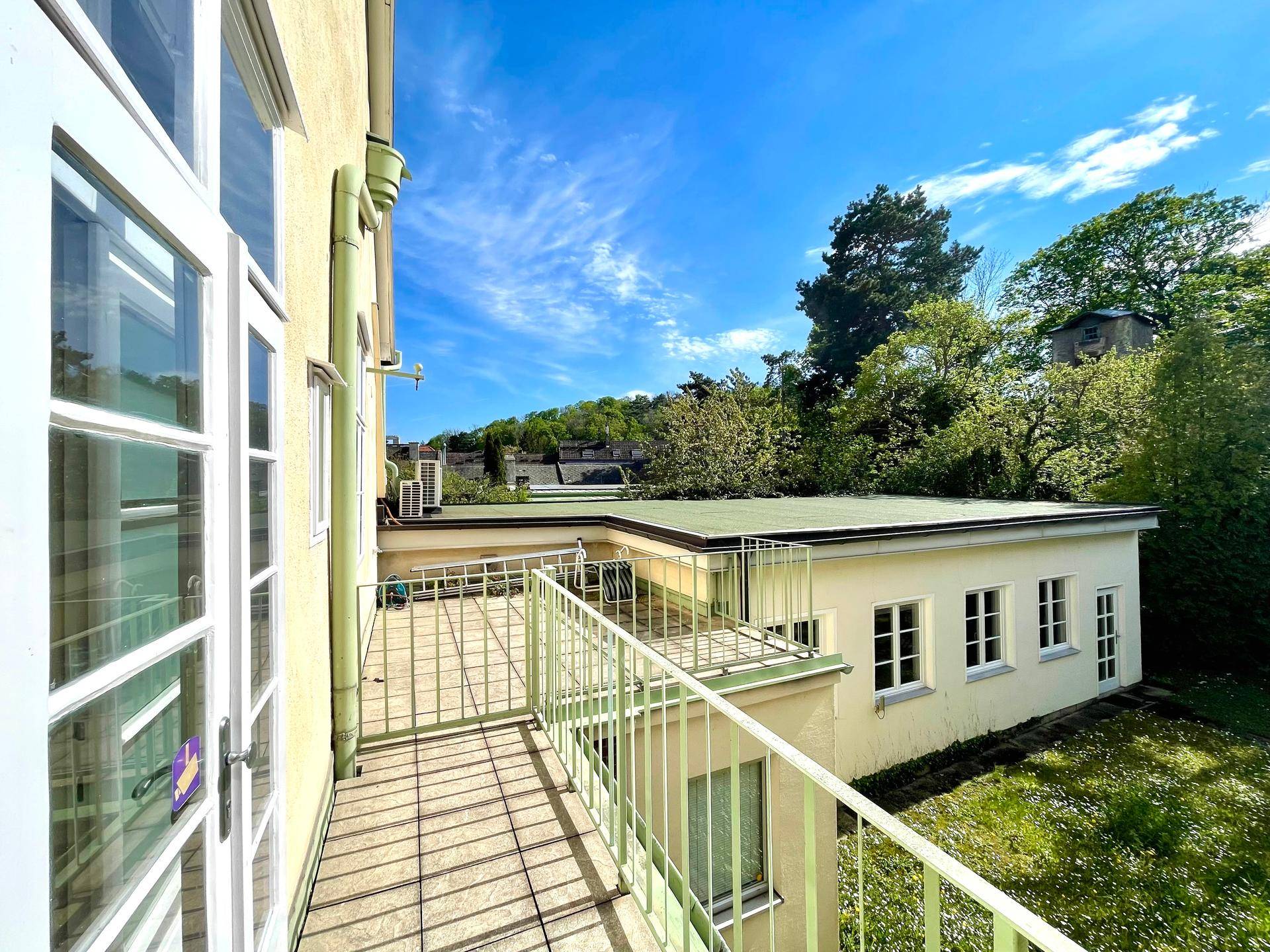 Großer Balkon mit Metallgeländer und weitem Blick auf die umliegende grüne Landschaft.