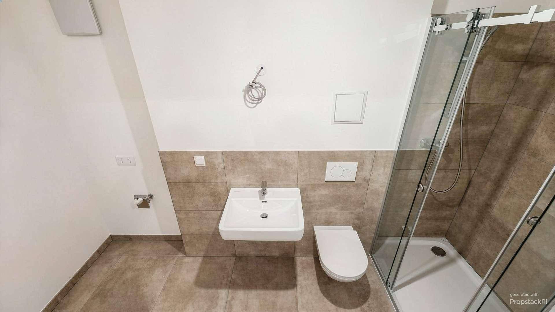 Modernes Badezimmer mit Dusche, WC und Waschbecken, ausgestattet mit beigefarbenen Fliesen.