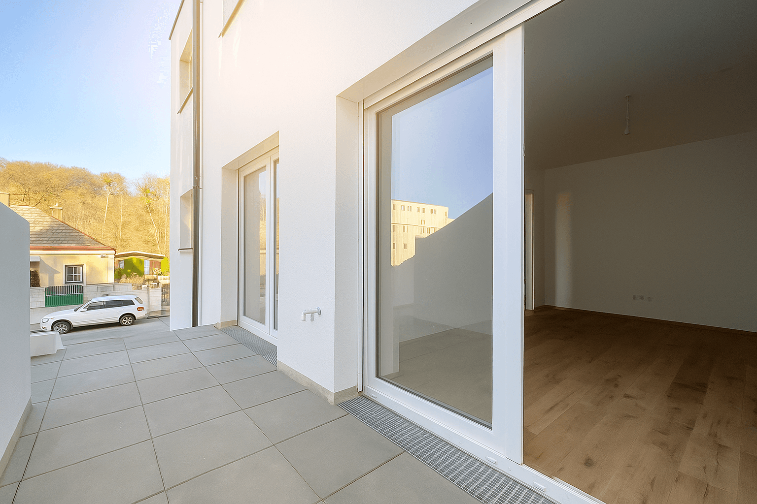 Helle Terrasse mit Fliesenboden und Blick auf die Umgebung, ideal für entspannte Stunden im Freien.