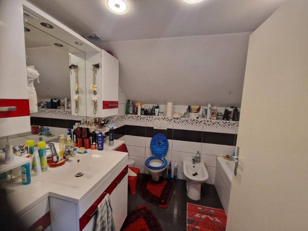Badezimmer mit Doppelwaschbecken, Toilette, Bidet und Badewanne unter Dachschräge.