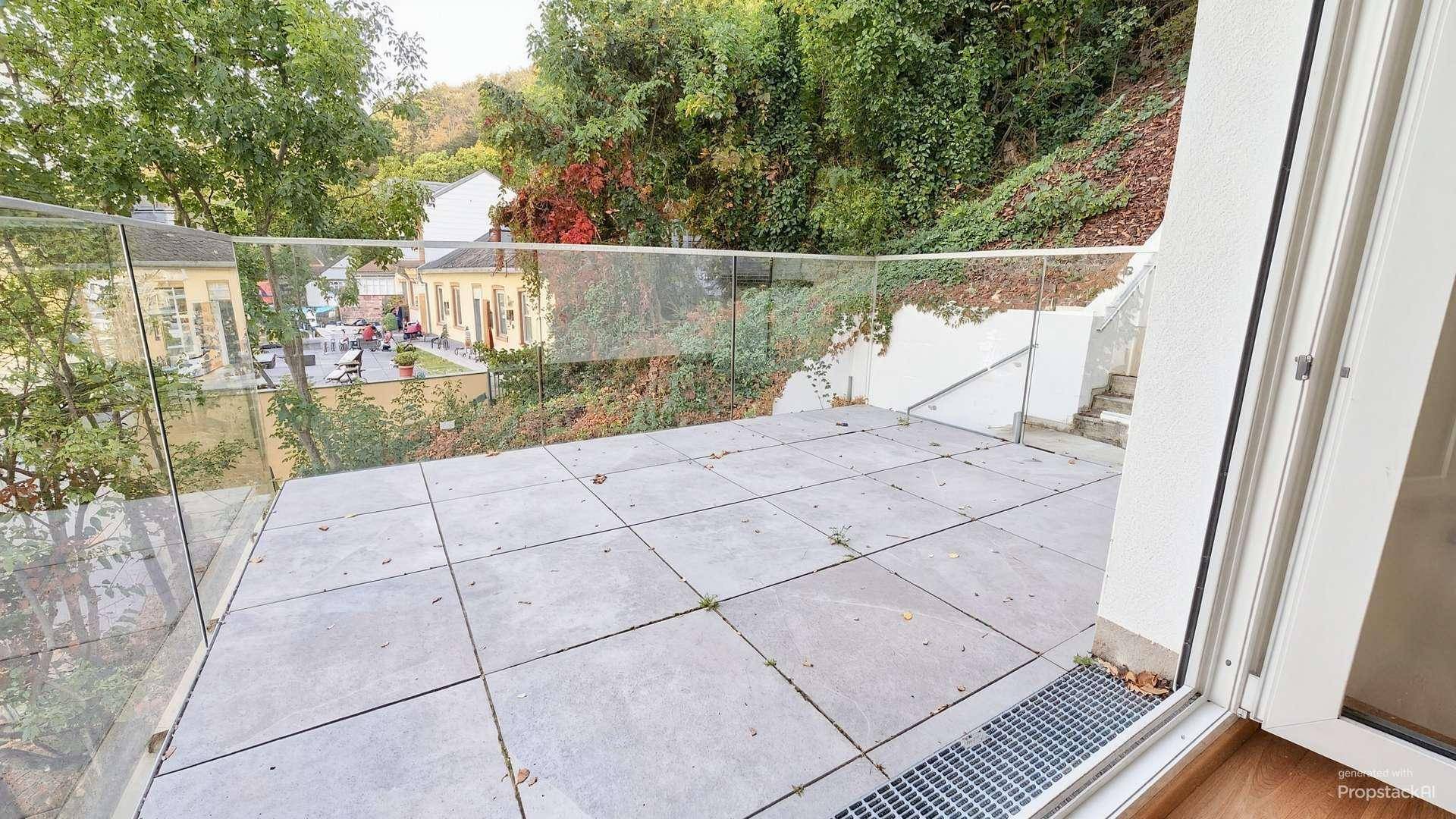 Geräumige Terrasse mit Glasgeländer und Blick ins Grüne, ideal für entspannte Stunden im Freien.