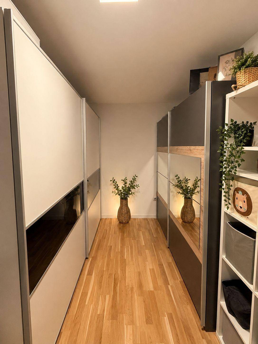 Begehbarer Kleiderschrank mit viel Stauraum, Spiegelflächen und hellem Holzboden.