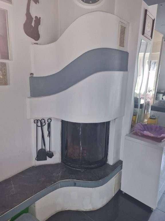 Moderner Kamin mit geschwungener Verkleidung und dunkler Ablagefläche.