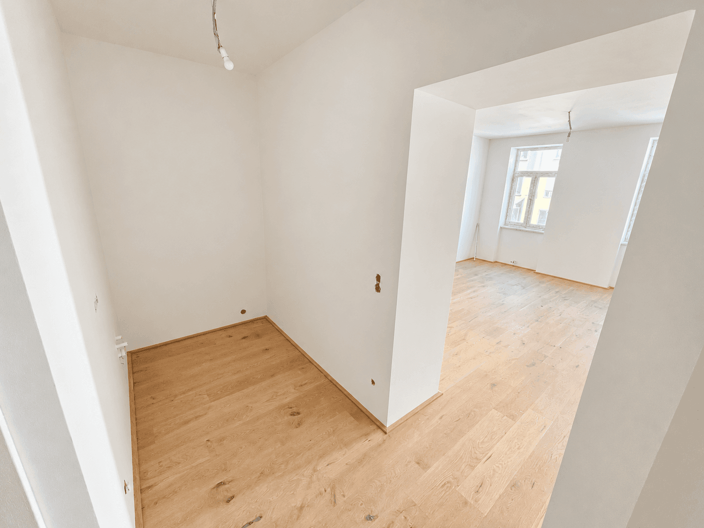 Heller Nebenraum mit Holzboden, der sich gut als Abstellraum oder Nische eignet.
