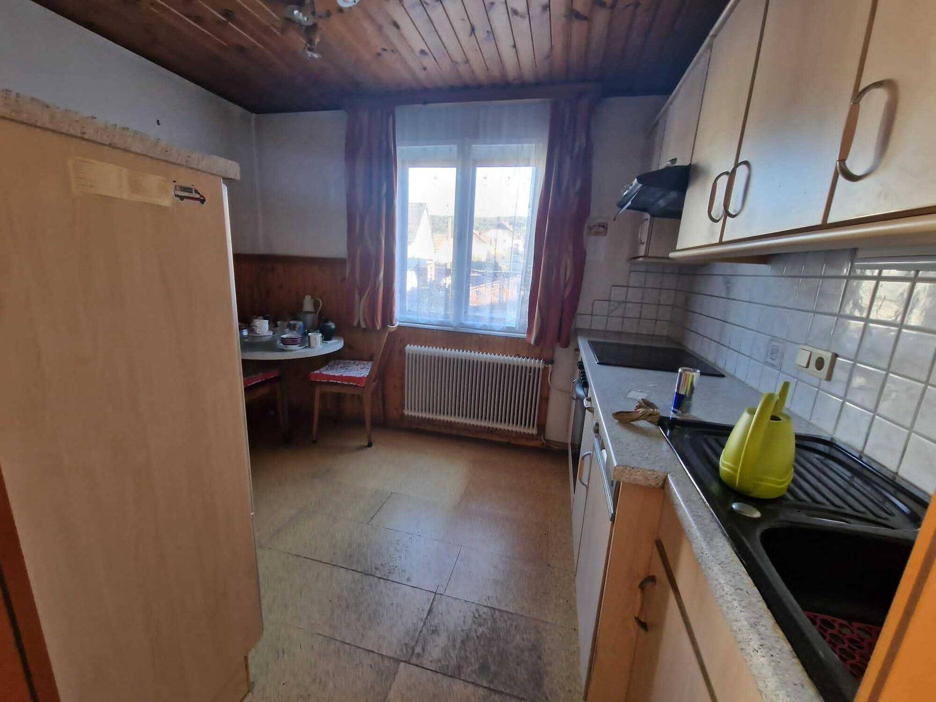 Funktionale Küche mit Fliesenboden, Holzdecke und einem Fenster mit Ausblick.