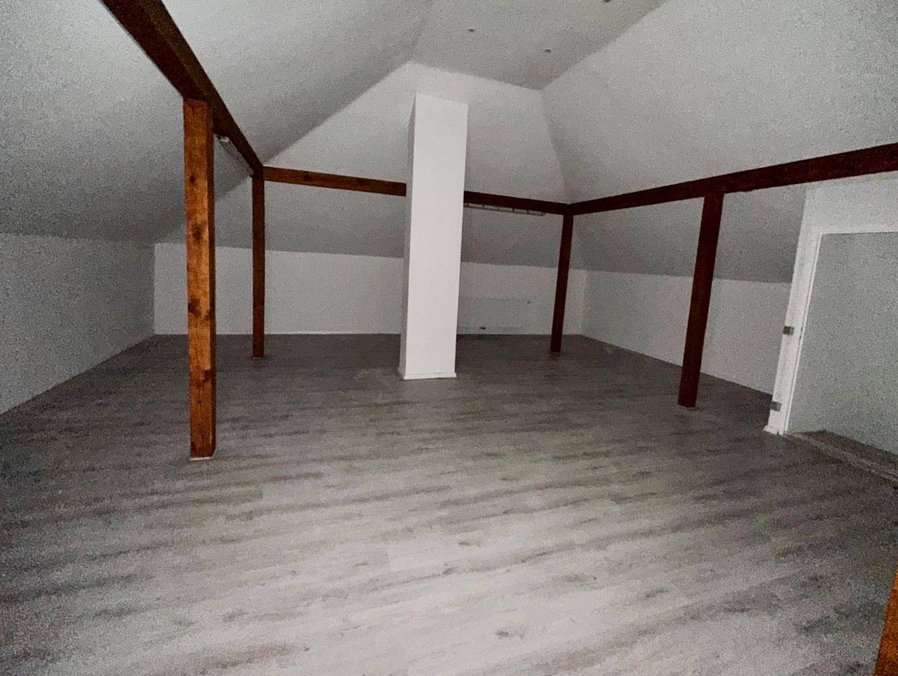 Geräumiger Dachboden mit sichtbaren Holzbalken und neuem Laminatboden, bietet Ausbaupotenzial.