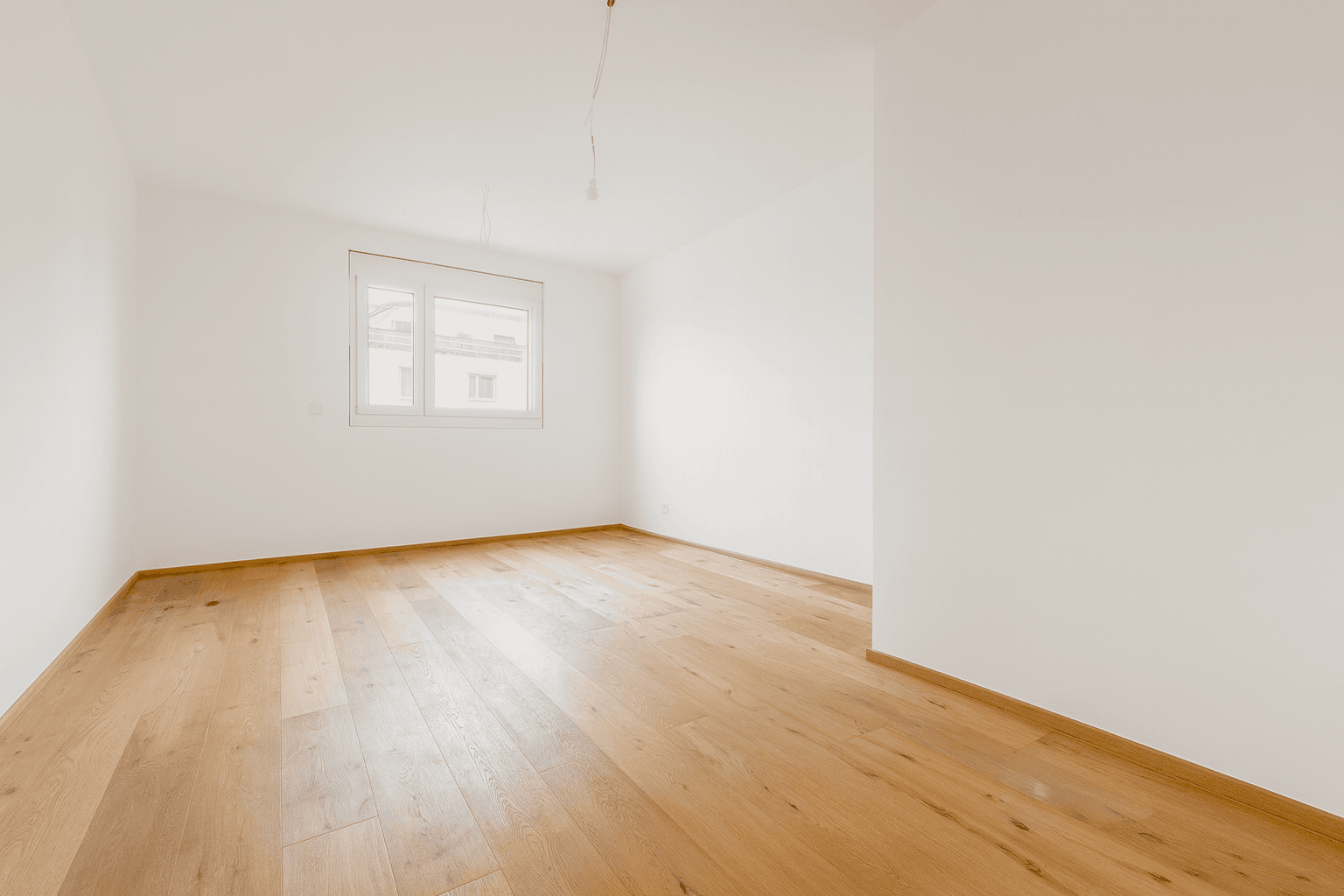 Helles Schlafzimmer mit Holzboden und einem Fenster, das viel Tageslicht in den Raum bringt.