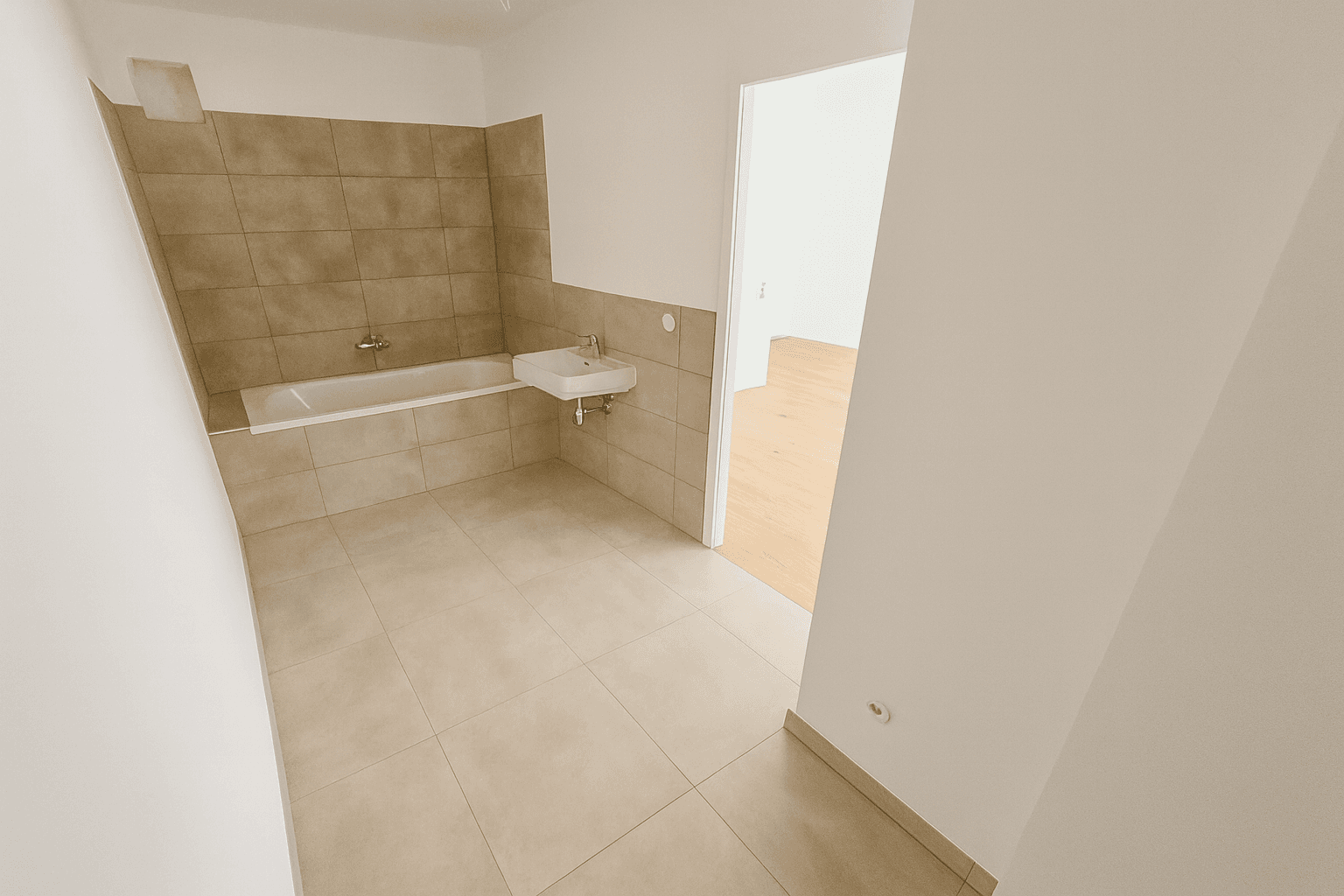 Geräumiger, heller Wohnbereich mit Holzboden und Zugang zu weiteren Räumen, bereit zur Gestaltung.