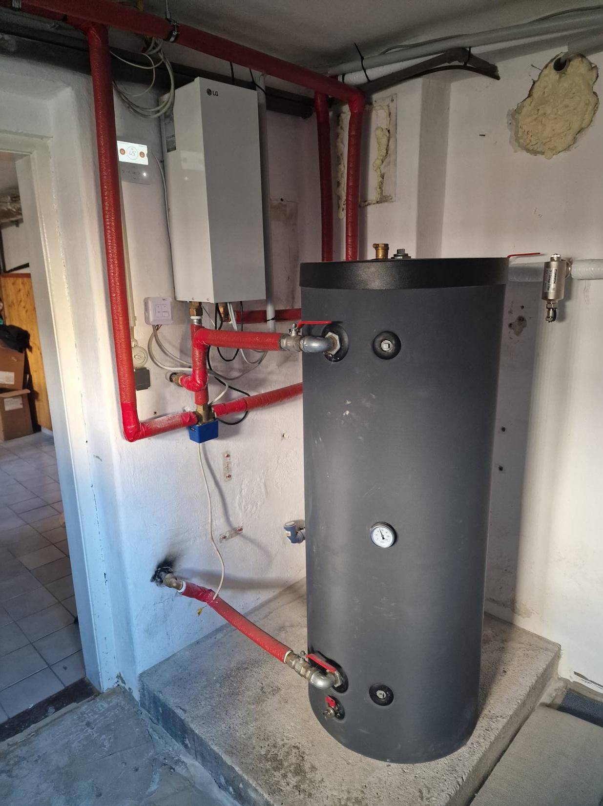 Warmwasserspeicher und Heizungsinstallationen in einem Technikraum.