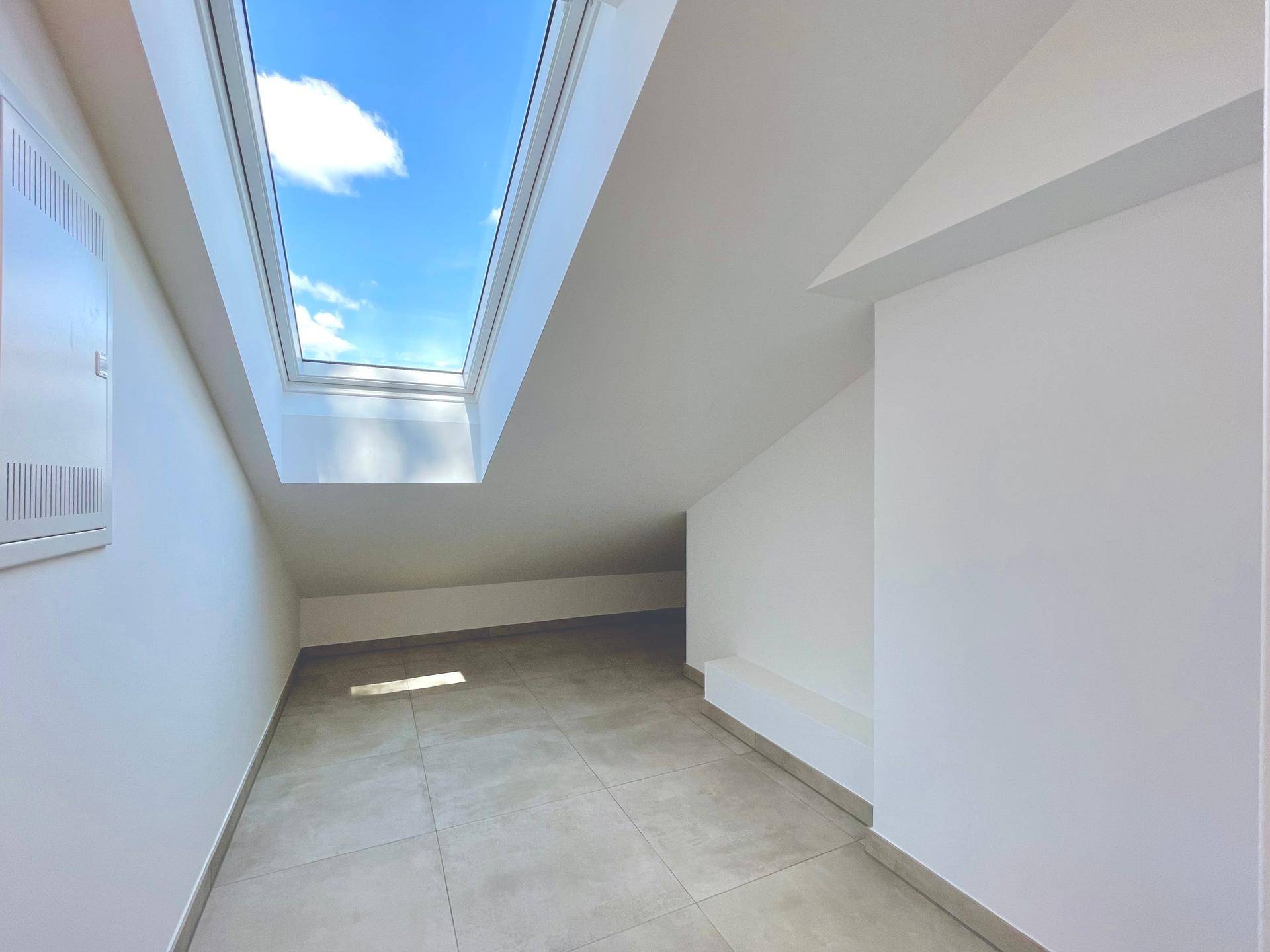 Heller Flur oder Abstellraum mit Fliesenboden und Dachfenster für natürliches Licht.