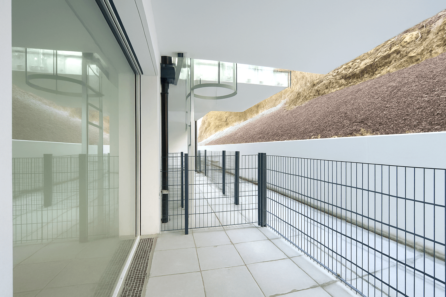 Geräumiger Balkon mit Fliesenboden und Glasgeländer, bietet einen weiten Blick auf die Umgebung.