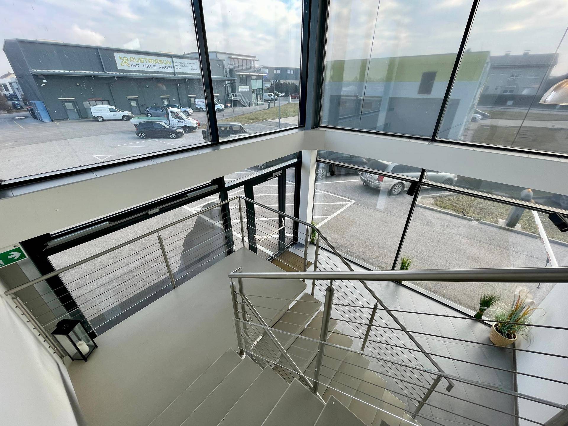 Moderne Treppe mit Glaswänden und Metallgeländern, die einen weiten Blick nach draußen ermöglicht.