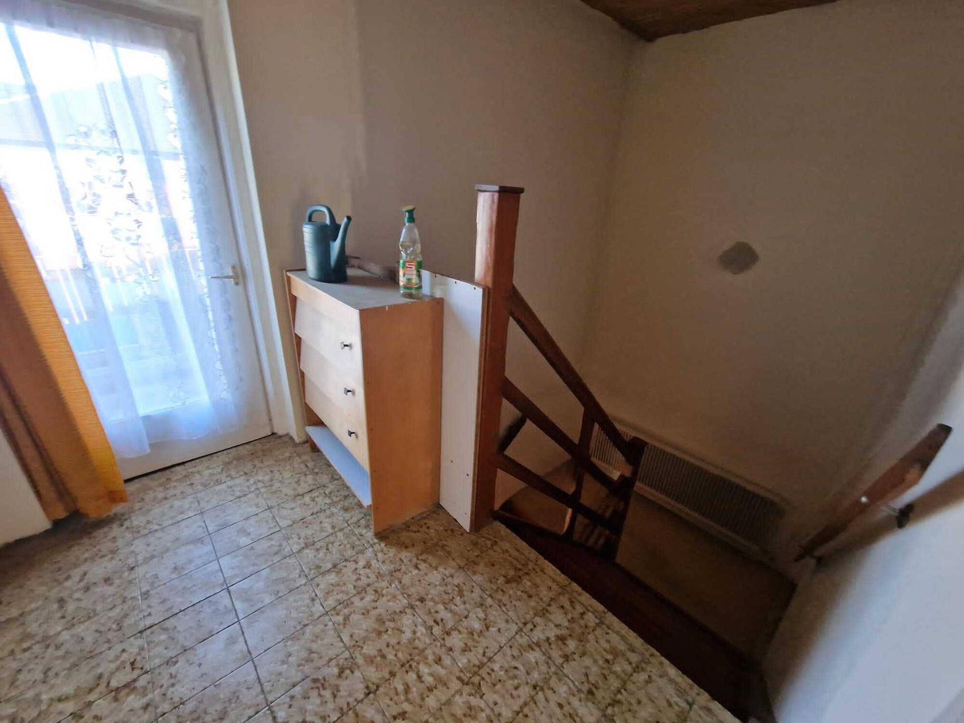 Treppenabsatz mit Fliesenboden, Fenster und Zugang zu einer weiteren Etage.