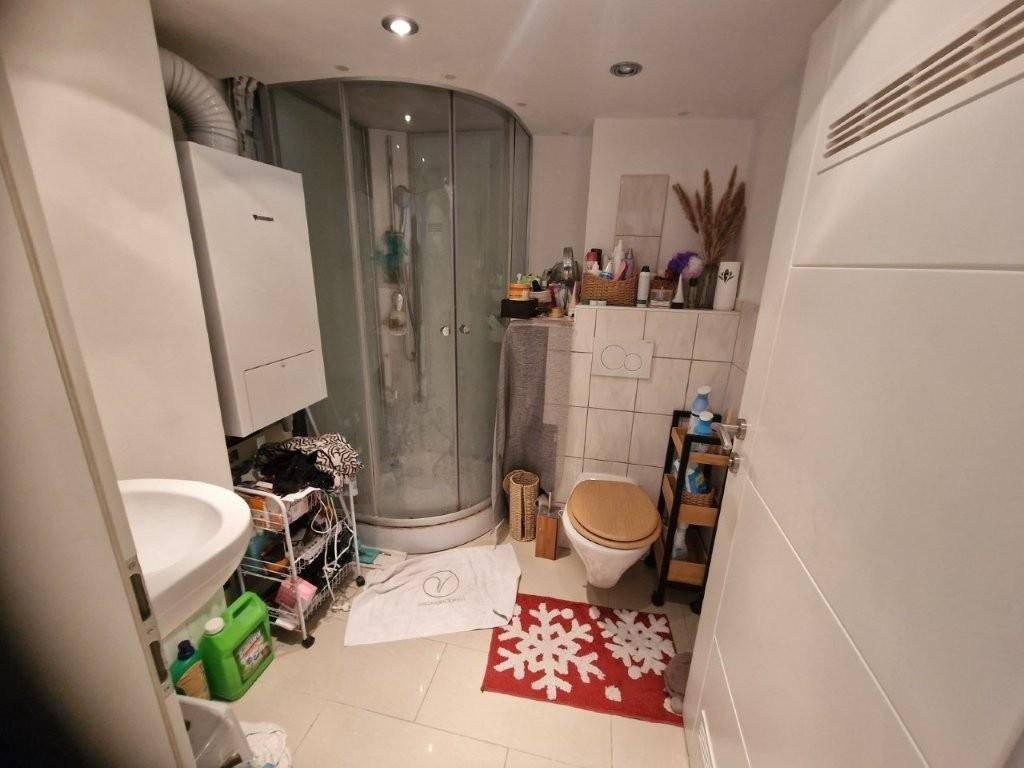 Kleines Badezimmer mit Duschkabine, Toilette und Waschbecken.