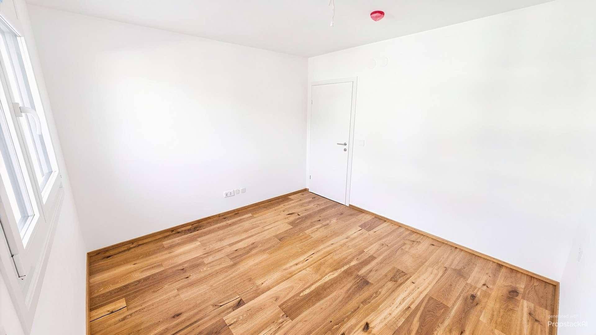 Helles Schlafzimmer mit Holzboden und einem Fenster, bietet eine ruhige Atmosphäre.