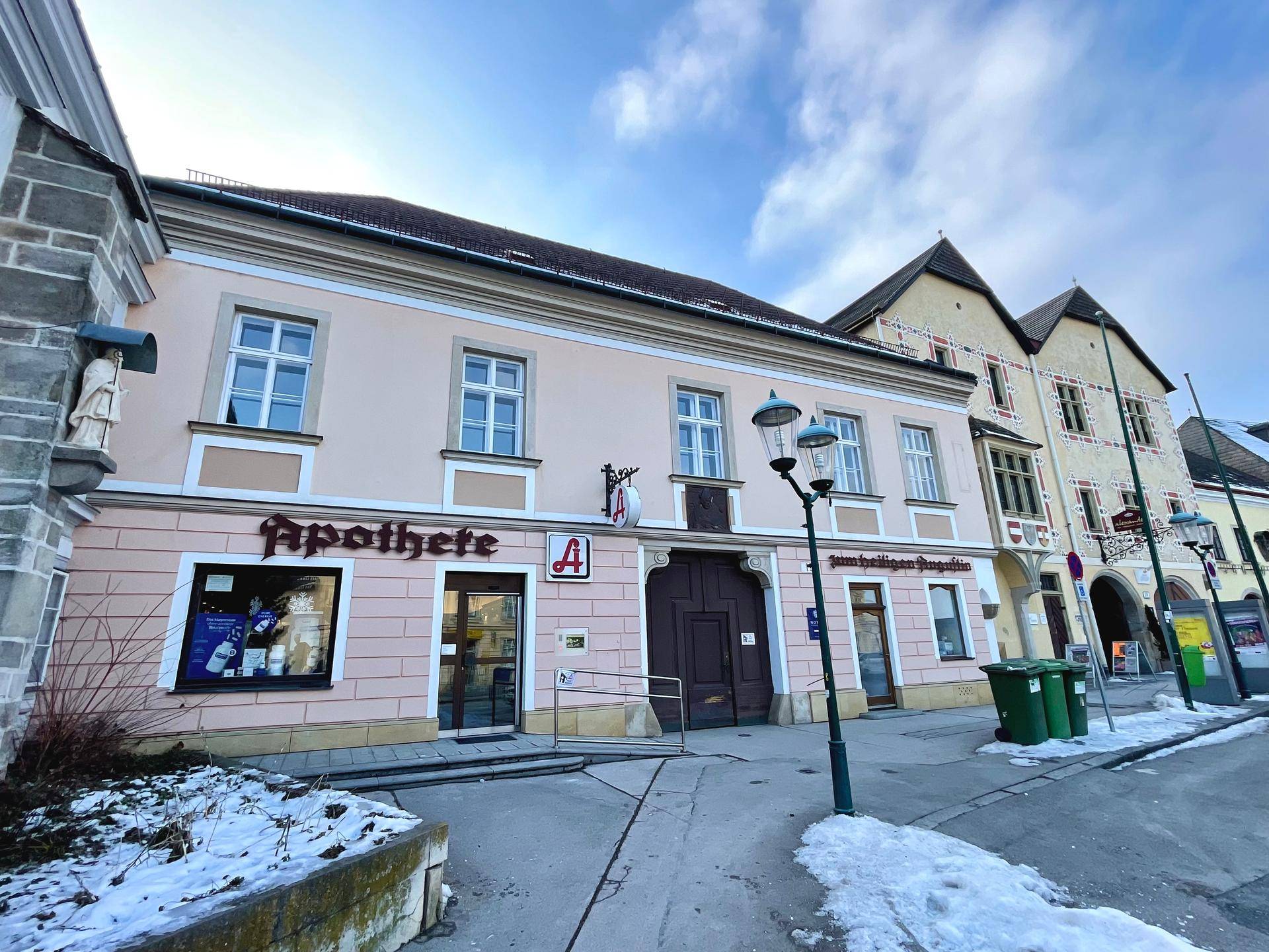 Historisches Gebäude mit Apotheke im Erdgeschoss und traditioneller Architektur in einer verschneiten Straße.