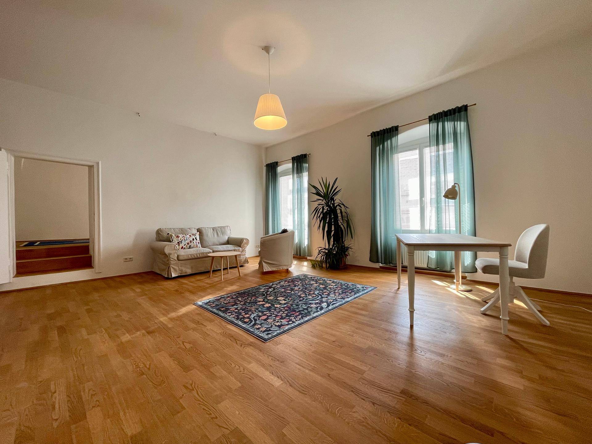 Heller Wohnbereich mit Holzboden, bequemen Sofas und einem Schreibtisch am Fenster.