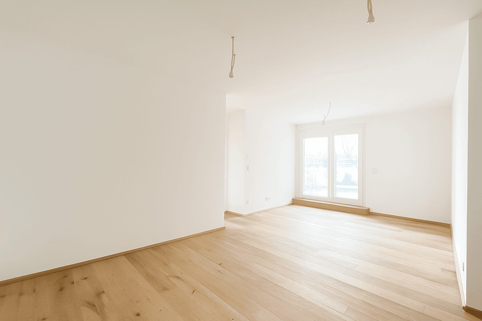 Heller, leerer Wohnraum mit Holzboden und großen Fenstern, die viel Tageslicht hereinlassen.