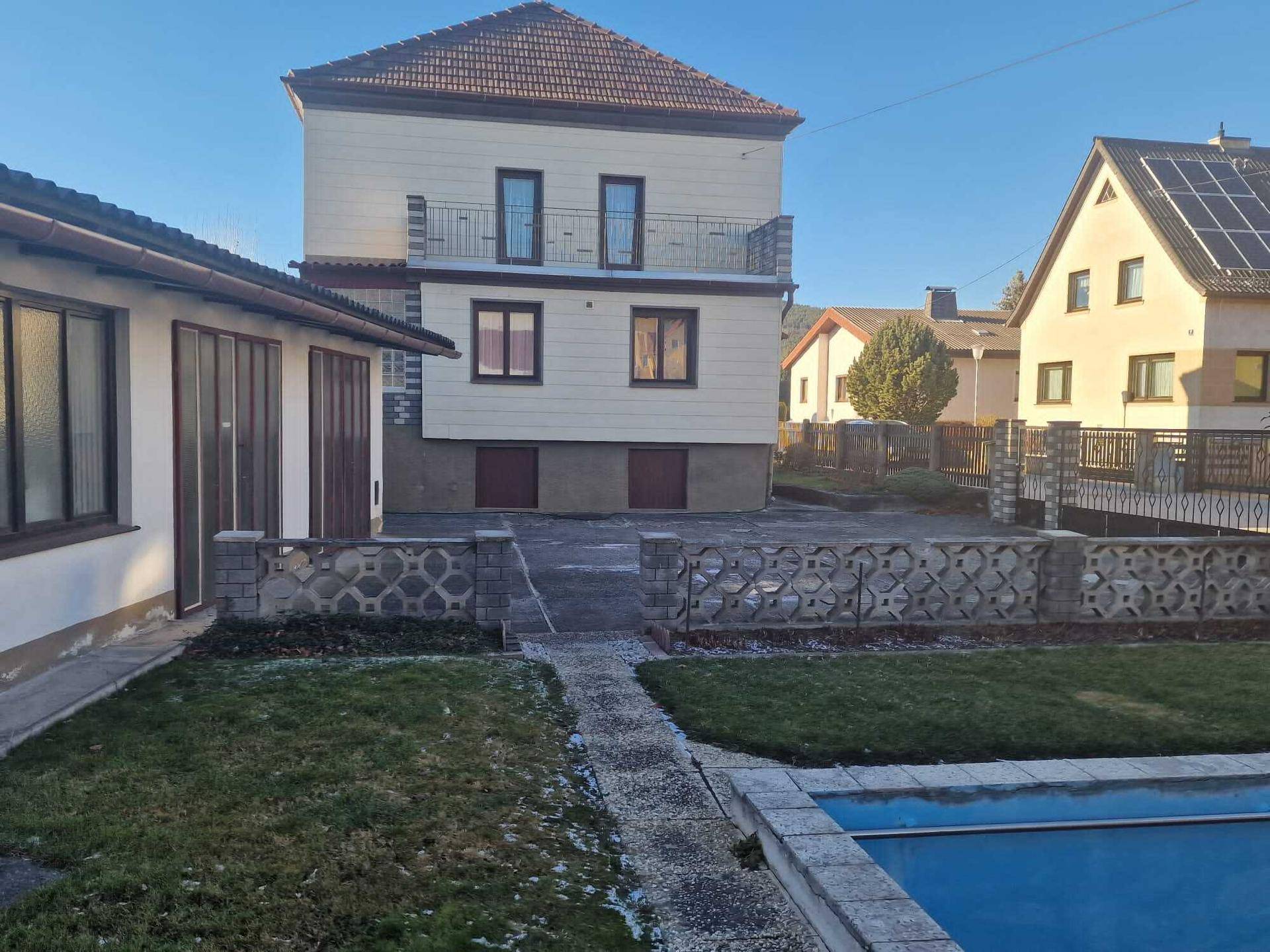 Gesamtansicht des Hauses mit Nebengebäude und einem Pool im Vordergrund.