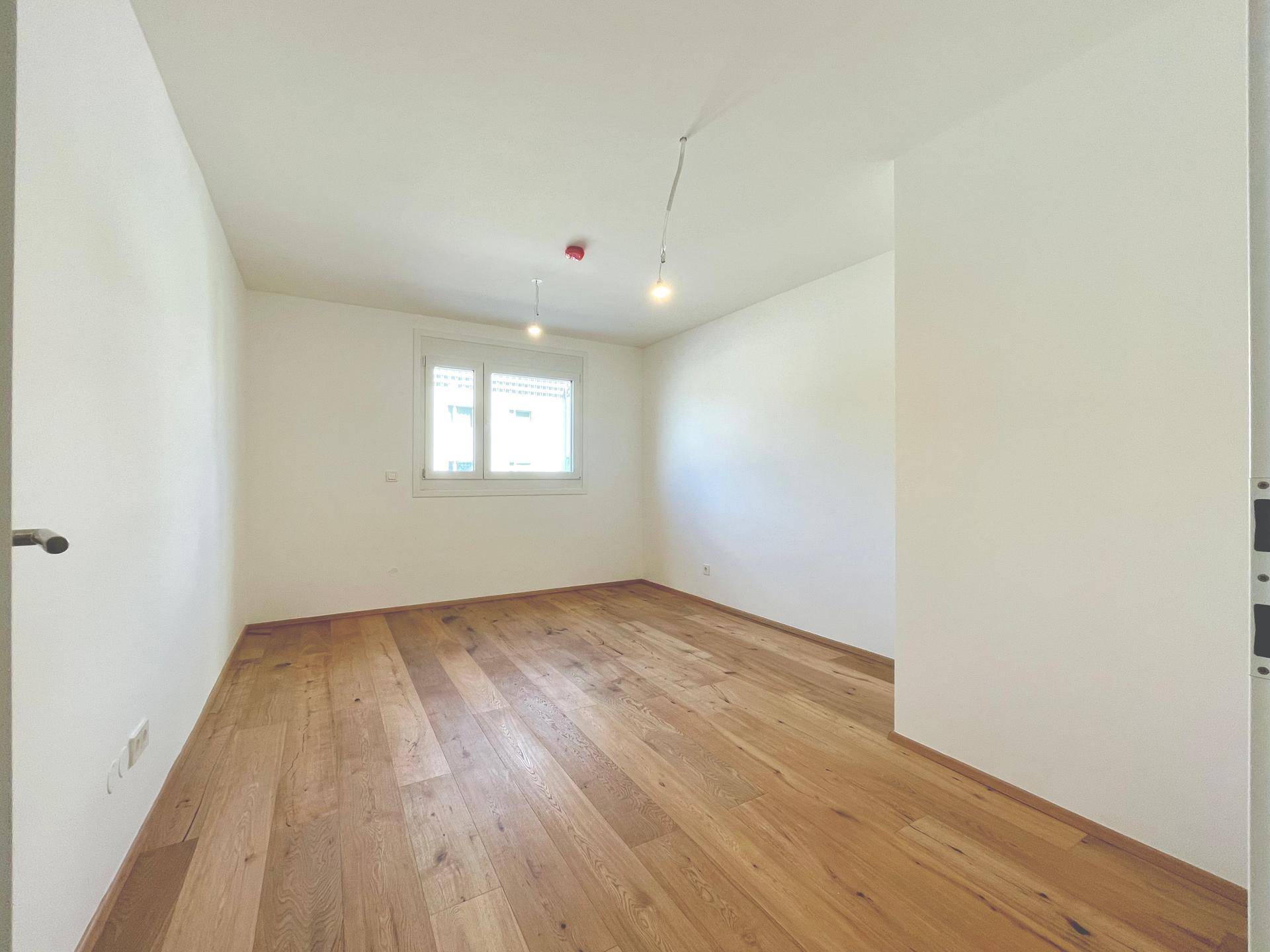 Unmöbliertes Schlafzimmer mit Holzboden und einem Fenster, ideal für individuelle Einrichtung.
