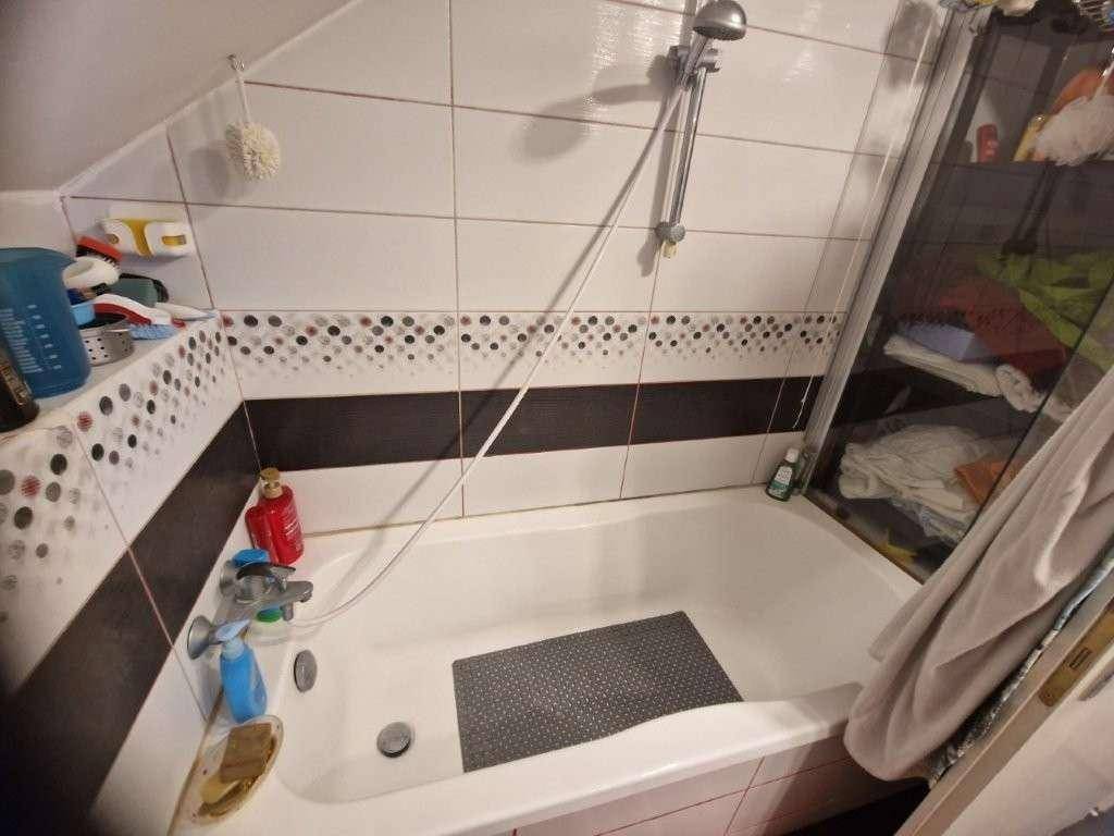 Badezimmer mit Badewanne und Duschvorrichtung unter der Dachschräge.