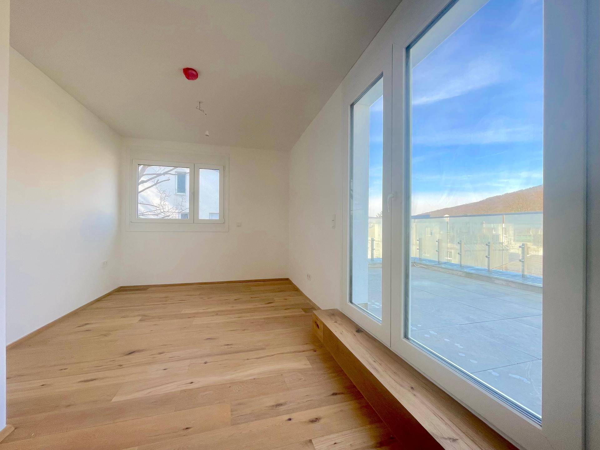 Helles Schlafzimmer mit Holzboden und Zugang zur großen Terrasse.