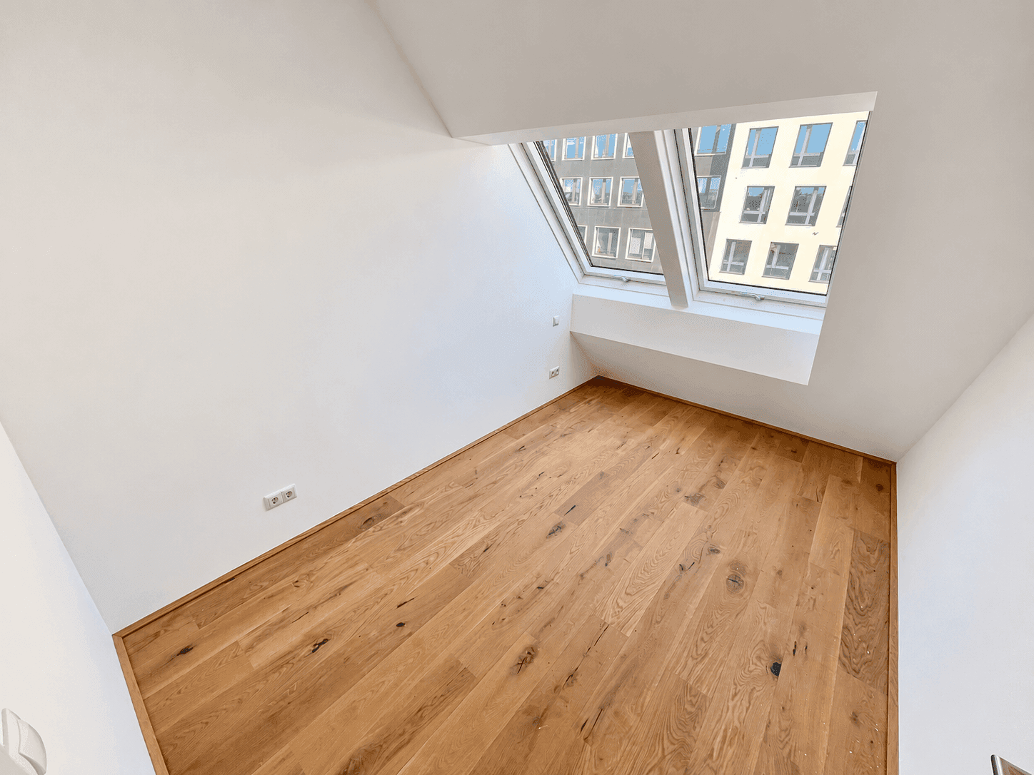 Helles Zimmer mit Holzboden und schrägen Dachfenstern, bietet viel natürliches Licht.