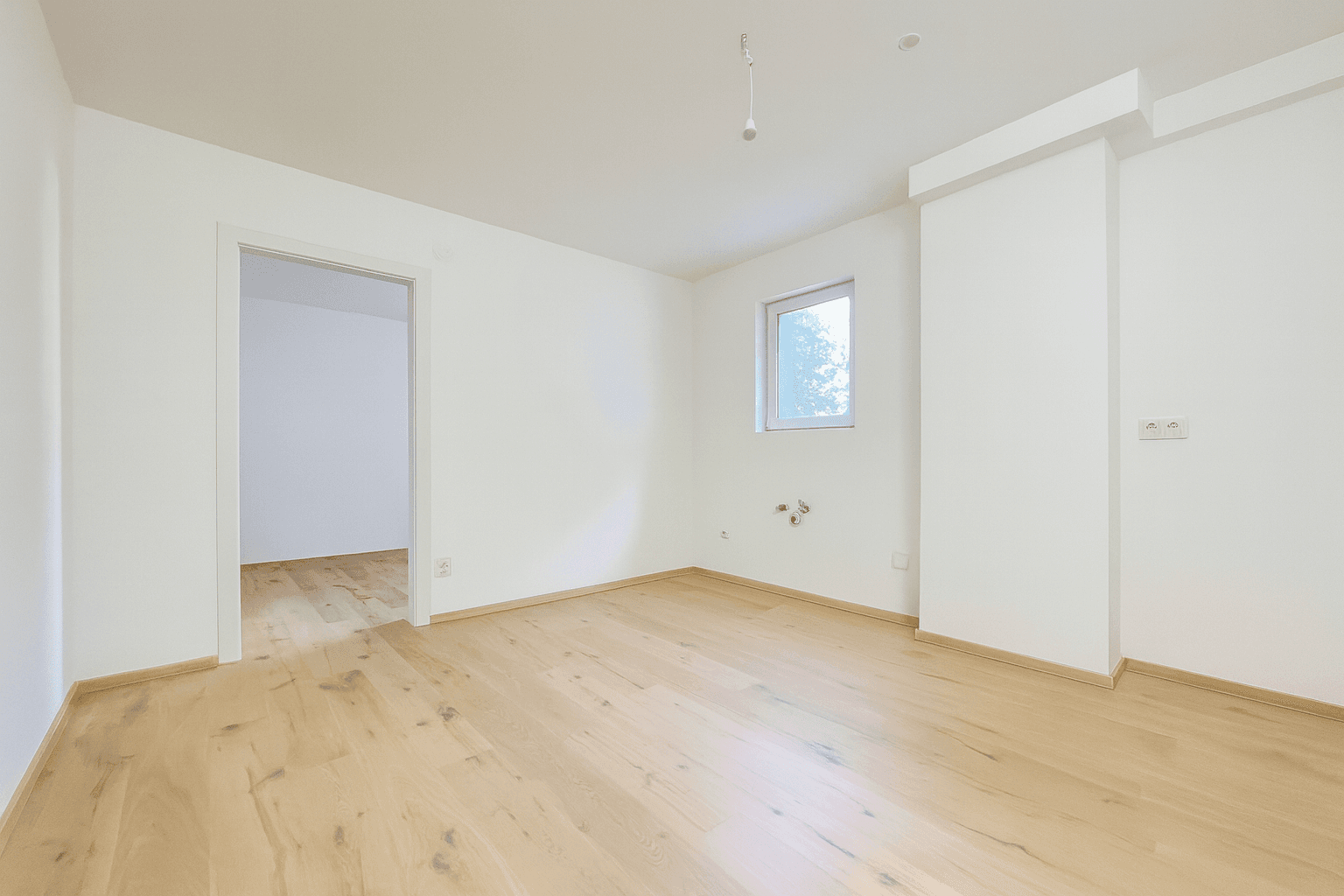 Helles Schlafzimmer mit Holzboden und einem Fenster, das viel Tageslicht in den Raum bringt.