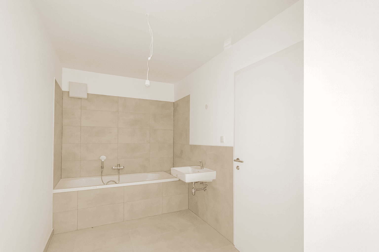 Modernes Badezimmer mit Badewanne, Waschbecken und Fliesen in neutralen Beigetönen.