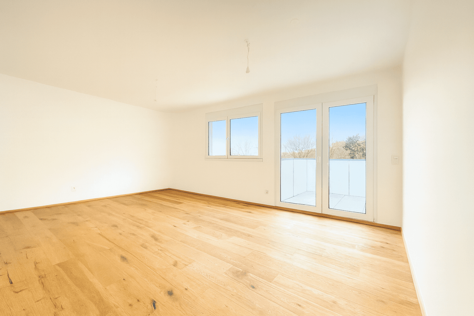 Helles Schlafzimmer mit Holzboden und großen Fenstern, die den Raum mit Licht füllen.