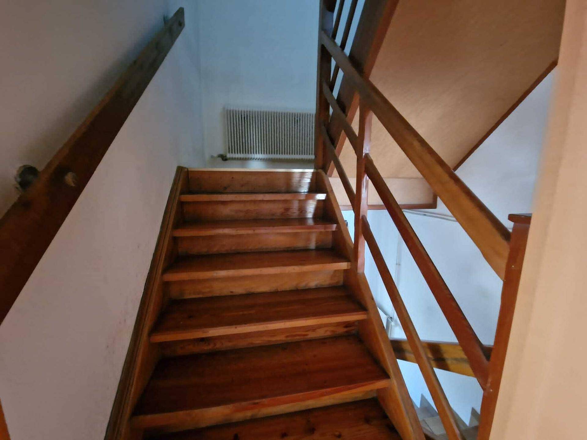 Holztreppe mit Geländer, die die verschiedenen Etagen des Hauses verbindet.