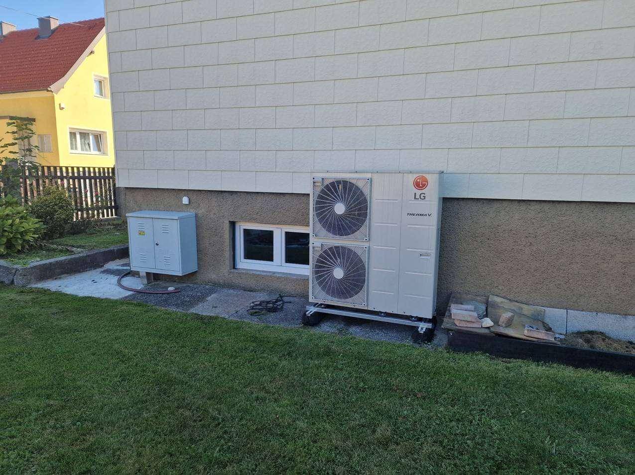 Nahaufnahme der Wärmepumpe von LG an der Hausfassade mit kleinem Kellerfenster.
