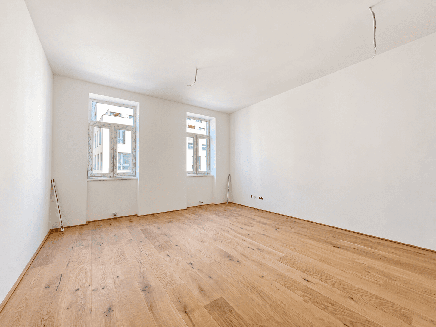 Geräumiges Zimmer mit Eichenparkett und zwei Fenstern, ideal als Schlafzimmer.