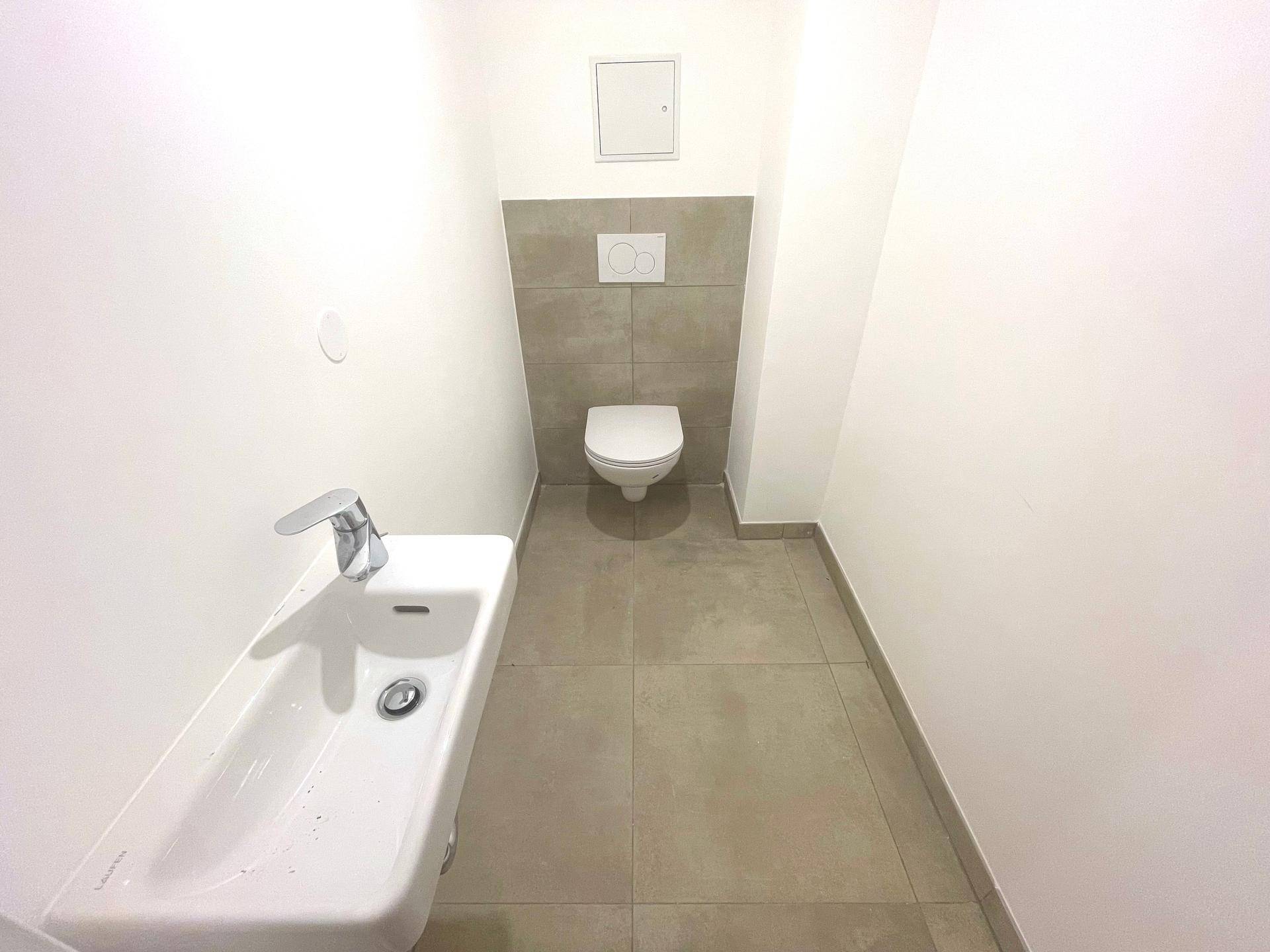 Praktisches Gäste-WC mit wandhängender Toilette und kleinem Waschbecken, modern gefliest.