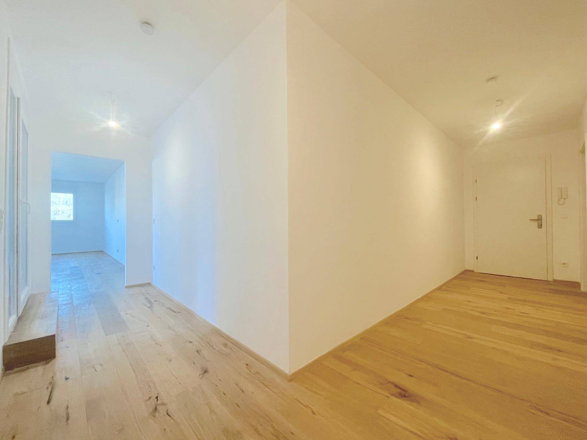 Heller Flur mit Holzboden und weiß gestrichenen Wänden, verbindet die verschiedenen Wohnbereiche.