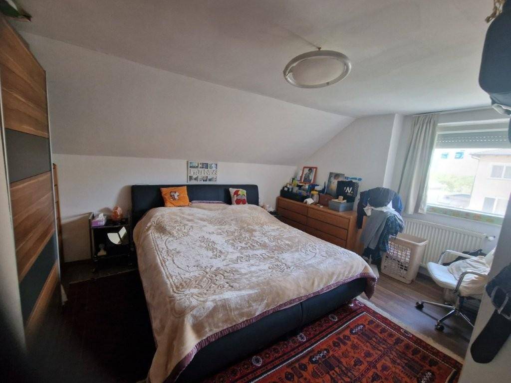 Gemütliches Schlafzimmer mit großem Bett, Dachschräge und Fenster.