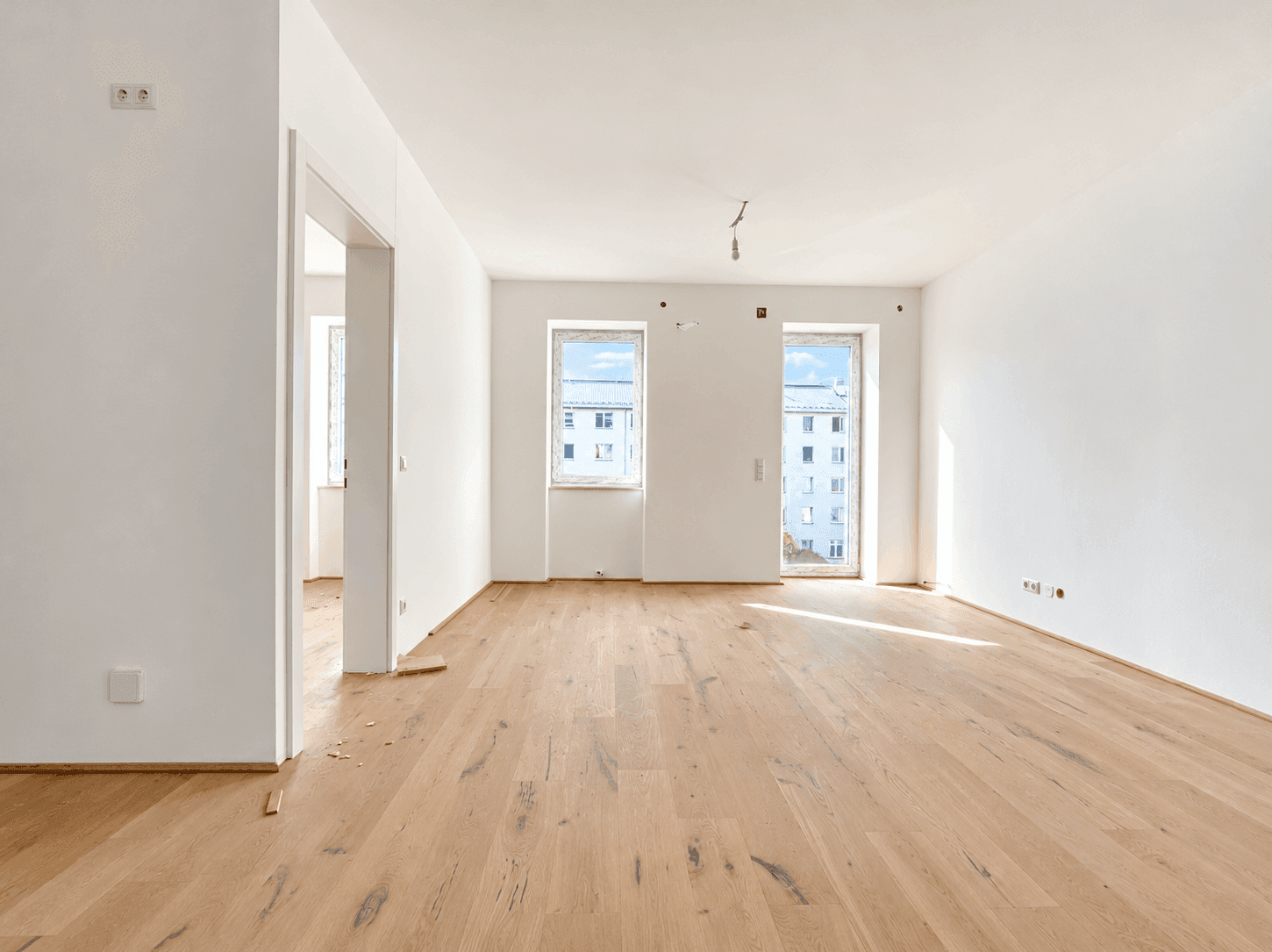 Großer, heller Raum mit Holzboden und zwei Fenstern, bereit für die Einrichtung.
