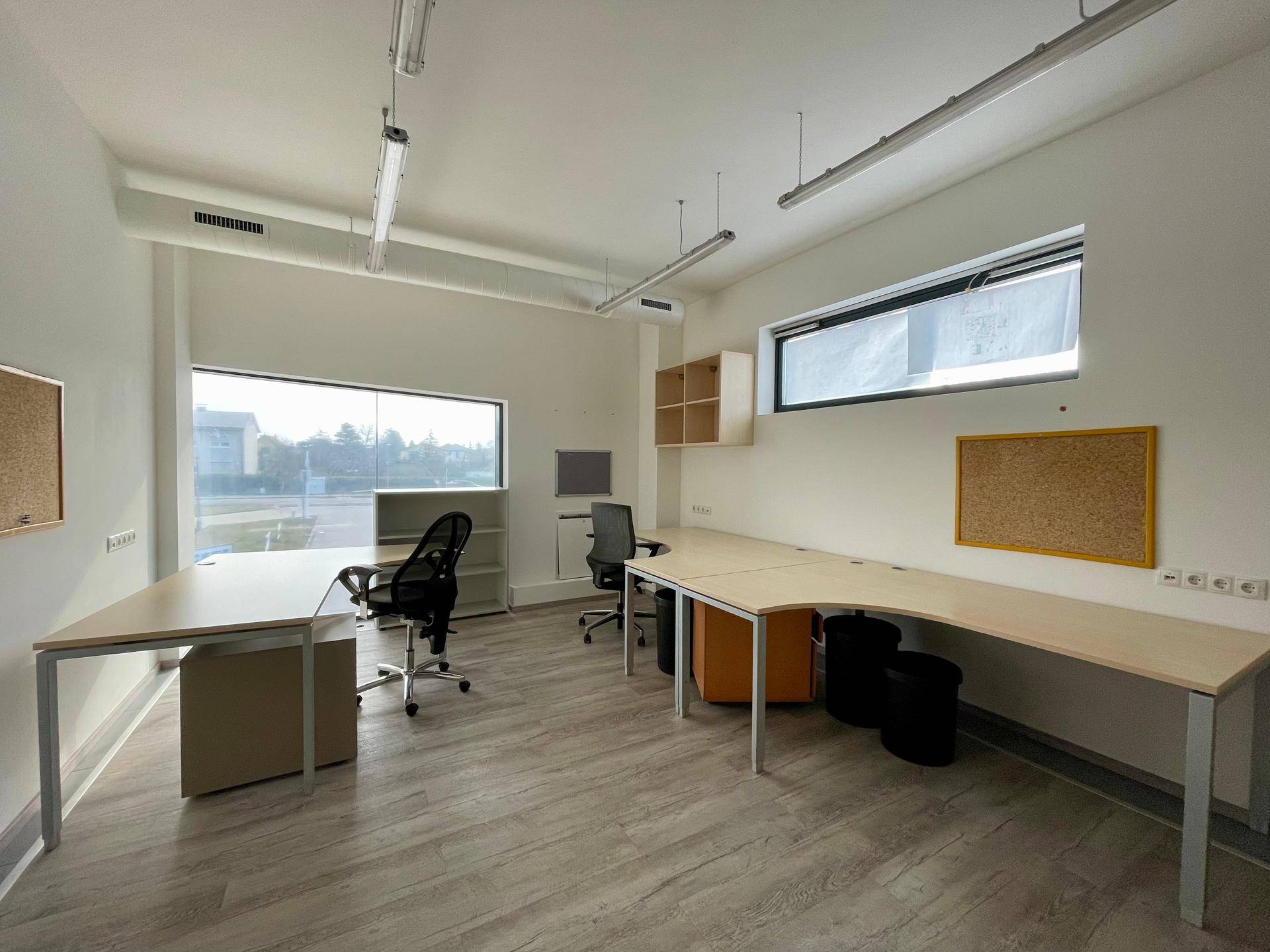 Helles Büro mit Holzoptik-Laminatboden, weißen Wänden und mehreren Fenstern für optimale Beleuchtung.