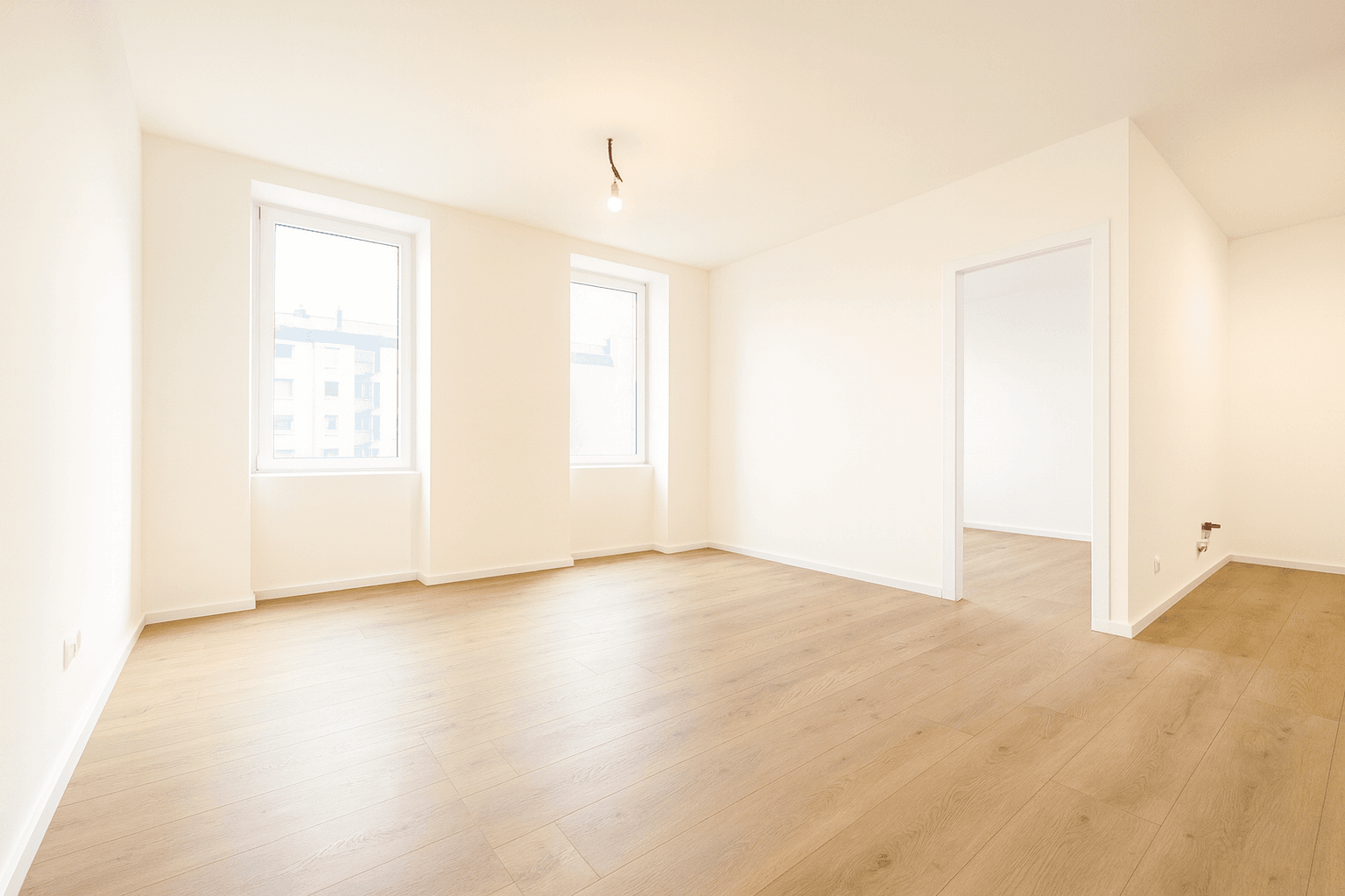 Großer, heller Raum mit Holzboden und Fenstern, ideal für offenes Wohnen.