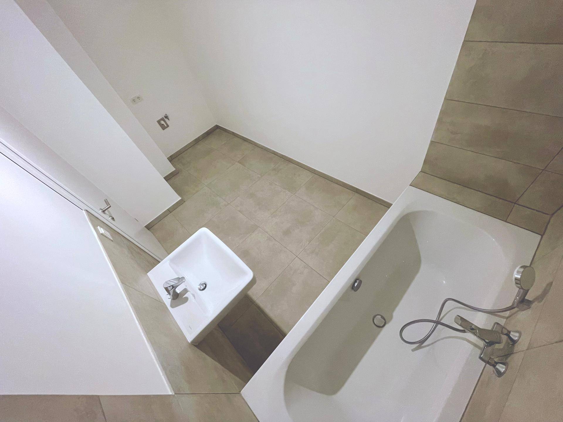 Modernes Badezimmer mit Badewanne und Waschbecken, ausgestattet mit hellen Fliesen.