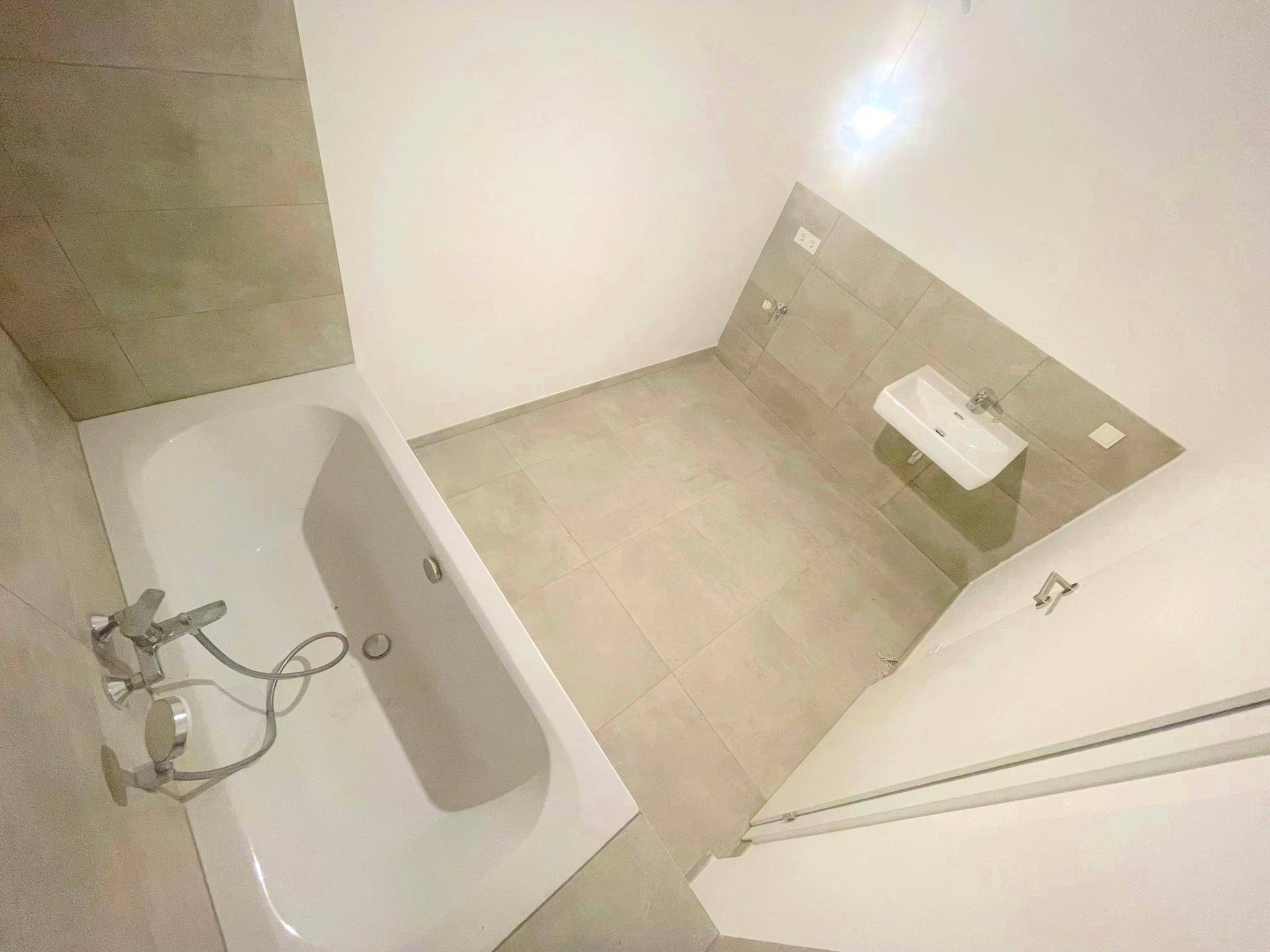 Modernes Badezimmer mit Badewanne und Waschbecken, ausgestattet mit hellen Fliesen.