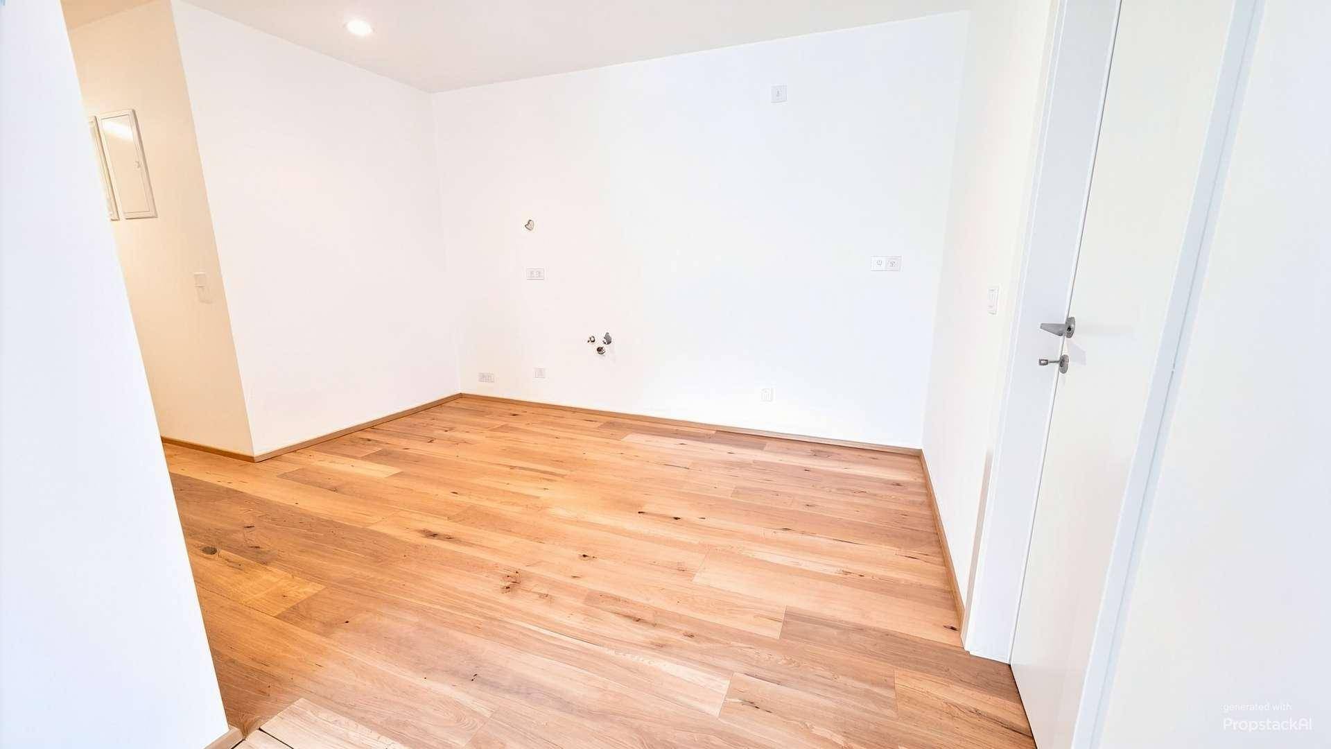 Leerer Raum mit Holzboden und weißen Wänden, vorbereitet für individuelle Nutzung.