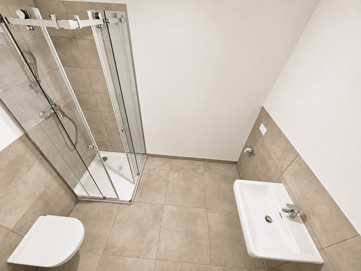 Modernes Badezimmer mit Duschkabine, Wand-WC und hellem Fliesenboden.