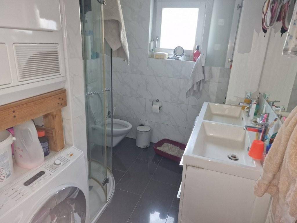 Badezimmer mit Dusche, Toilette, Waschbecken und Waschmaschine.