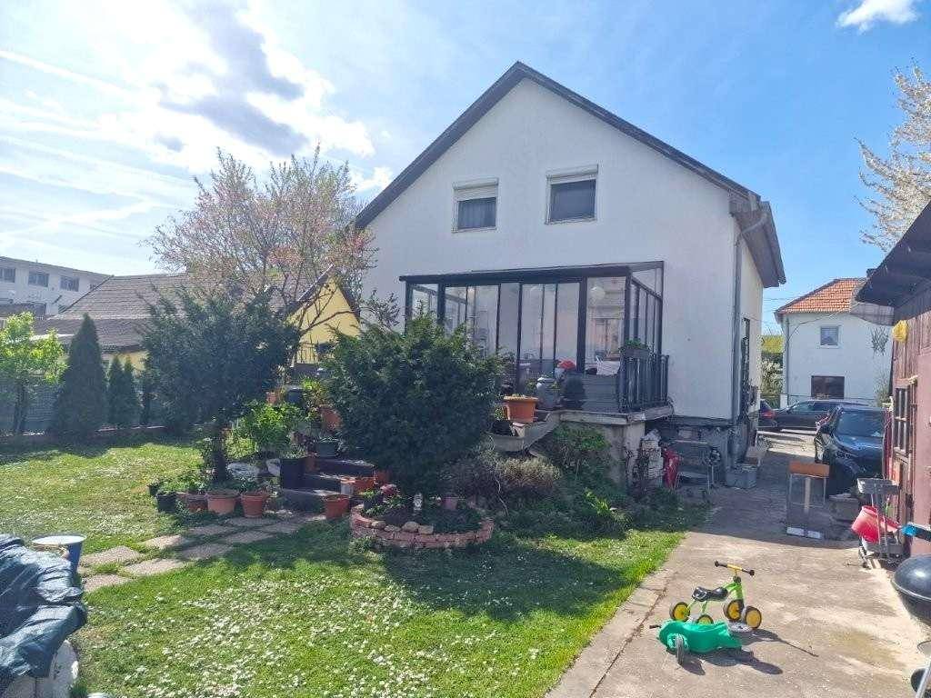 Rückansicht des Hauses mit Garten, Rasenfläche und verglastem Wintergarten.