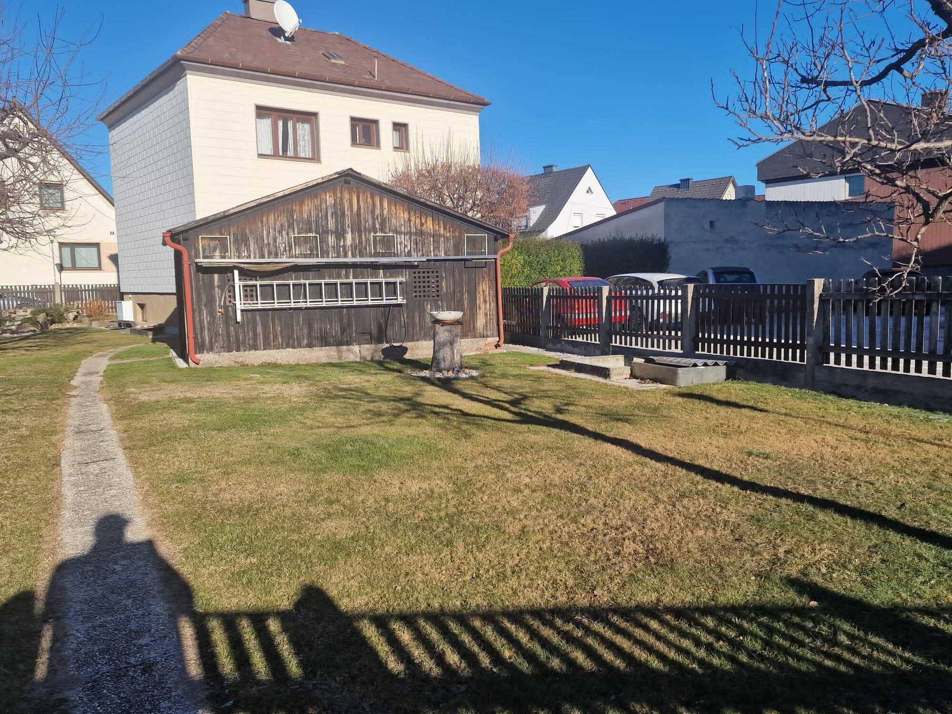 Großer Garten mit Rasenfläche und einem Holzschuppen im hinteren Bereich.