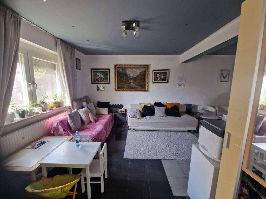 Wohnzimmer mit dunklen Fliesen, zwei Sofas und einem Kinderspieltisch.